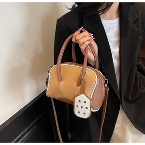 Detail of a brown two-tone leather handbag with blue contrast stitching and white charm