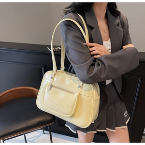 Détail du sac messager en cuir jaune crème avec poche zippée et texture gaufrée
