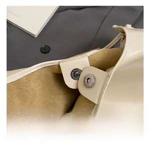 Detail of magnetic buckle and suede lining on a beige leather minimalist tote bag
