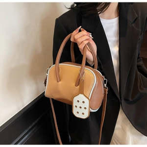 Detail of color-block Boston bag with blue piping, twin handles and leather tag