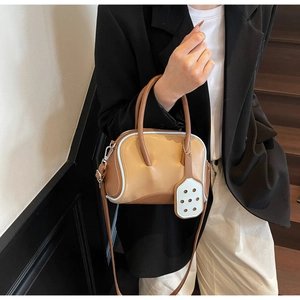 Detailed view of bicolor brown and blue leather bowling bag with dot pendant on stairs