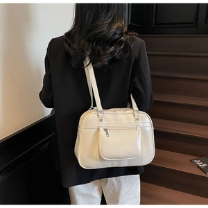 Close-up of beige PU leather messenger bag with embossed letters and front zipper pocket