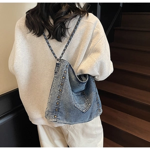 Close-up of vintage blue denim tote bag with bronze rivets and chain shoulder strap detail