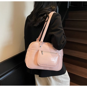 Détail du sac messager rose brillant avec logo Noronoro en relief et fermeture éclair frontale