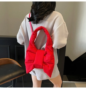 Detail of red oversized bow tote bag in quilted nylon with thin shoulder strap