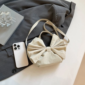 Sac fourre-tout beige en toile avec nœud et bandoulière réglable sur une veste grise
