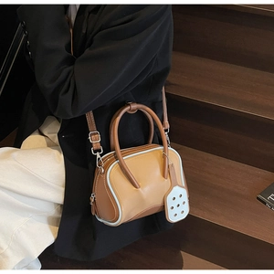 Detalle de bolso bowling en caramelo y azul con asas dobles y etiqueta blanca