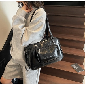 Détail du sac de messager noir brillant avec logo embossé et finitions argentées
