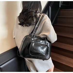Gros plan sur le sac messager en cuir verni noir avec logo Noronoro en relief détaillé