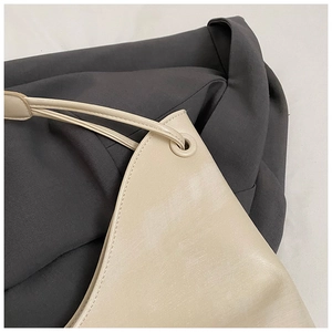 Detail of beige PU leather shoulder bag featuring fine stitching and round hardware eyelets