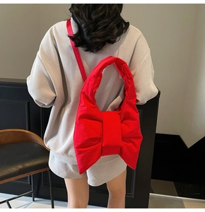 Close-up of bright red oversized bow tote bag in quilted nylon with a thin shoulder strap