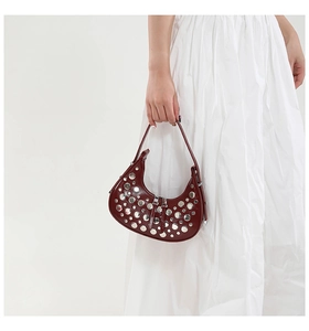 Detail of burgundy crescent bag with silver metallic rivets and sleek leather finish
