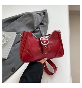 Details von roter Lackledertasche mit silbernen Nieten und einer großen Metallschnalle