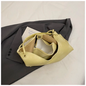 Detail of light yellow tote bag with matching inner pouch on a grey suit background