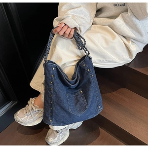 Detail of vintage denim tote bag featuring copper rivets and woven metal chain strap