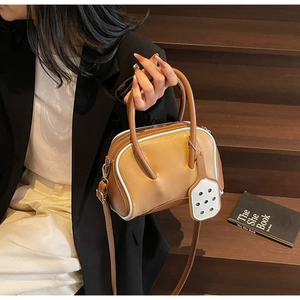 Bolso bowling marrón con ribete azul claro mostrado por modelo en escalera de madera