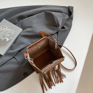 Brown rivet tassel crossbody bag with silver hardware on a professional scene