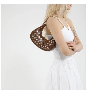 Detail of a brown moon bag with vintage silver rivets and matte leather texture