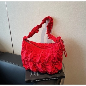 Macro shot of red ruched fabric bag with a decorative ribbon and metallic zipper puller