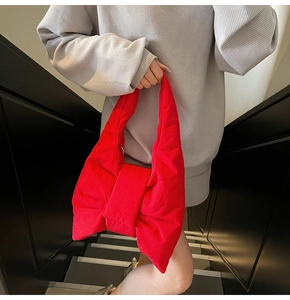 Close-up of a large red bow-shaped puffer shoulder bag with soft quilted nylon texture