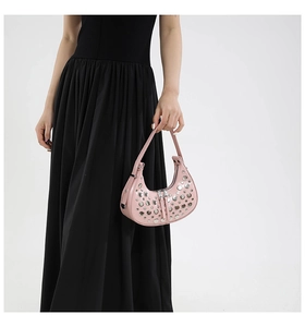 Close-up of pink crescent bag with silver rivets and dual zipper detail on leather