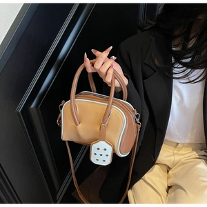 Detail of color-block bowling bag in ginger and brown leather with blue trim and charm