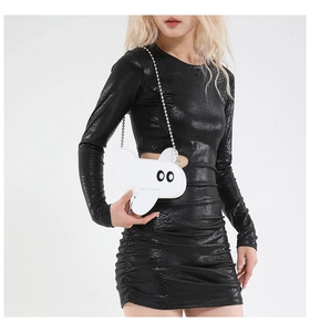 Close-up of airplane shaped white leather crossbody bag with chain on snake print dress