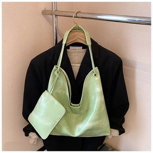 Detail of light green tote bag set with vintage textured faux leather on a clothing hanger