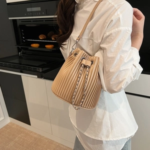 Elegant beige pleated bucket bag with metal chain drawstring and leather shoulder strap