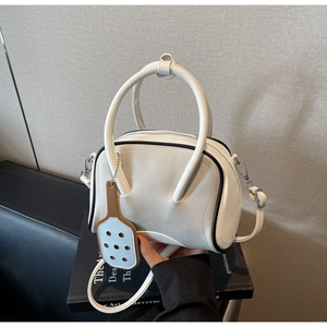 Detail of white bowling bag featuring black trim and racket-shaped decorative pendant