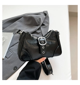 Detail einer schwarzen glänzenden Motorrad-Handtasche mit großer Silberschnalle und Ösen