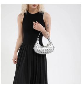 Detail of silver crescent bag with metallic studs and tassel zipper on a model