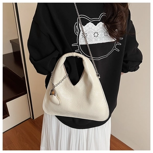 Detail of creamy white geometric handbag with wrinkled patent leather and heart charm