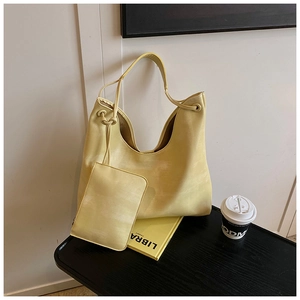 Detail of yellow large tote bag with matching zipper pouch on a black wooden desk