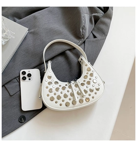 Detail shot of white crescent bag with silver metallic studs and leather zipper pulls