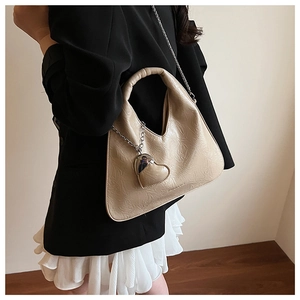 Detail of beige pleated leather shoulder bag with silver chain and heart charm