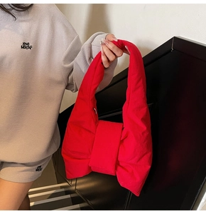 Detail of a bright red bow-shaped tote bag showing padded nylon fabric and plush texture