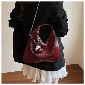 Detail of burgundy patent leather dumpling bag with heart charm and silver chain strap