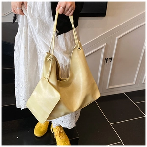 Close-up of light yellow large capacity tote bag with matching inner pouch on shoulder
