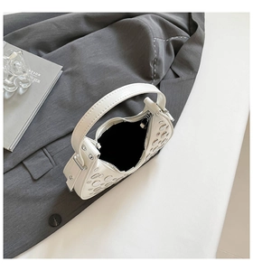 Detail of white half-moon bag featuring silver studs and smooth faux leather texture