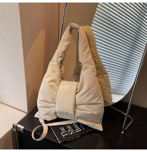 Detail of beige quilted nylon tote bag featuring a large decorative bow and slim shoulder strap