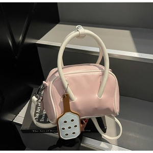 Pink and white Boston bag with petal charm on minimalist display stand detail view