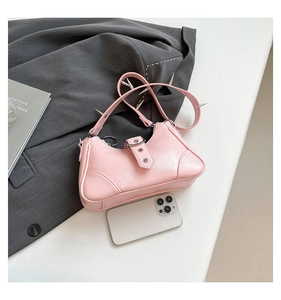 Rosa Punk-Umhängetasche mit silbernen Nieten und Schnallen, neben einem Smartphone