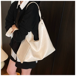 Beige oversized leather tote bag with a matching pouch shown on shoulder from a side view