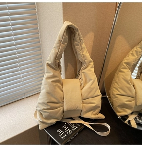 Detailed close-up of cream quilted nylon tote with puffy texture and soft shoulder straps
