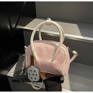 Pink bowling handbag with cream handles and blue paddle charm held by model