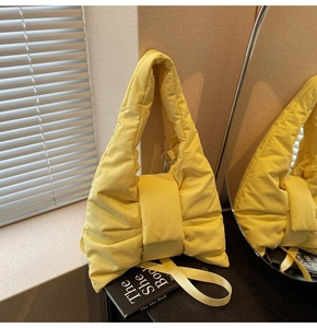 Detail of quilted yellow tote bag showing padded nylon fabric and bow-shaped design