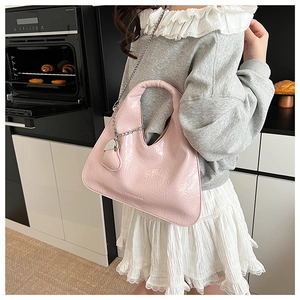 Pink glossy ruched crossbody bag with silver chain strap and heart charm worn by model