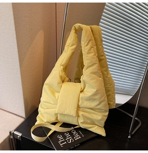Detail of a puffy yellow nylon tote bag with bow design and quilted texture finish