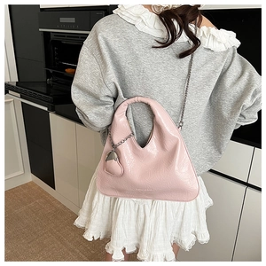 Detail of light pink patent leather handbag with silver chain and heart charm